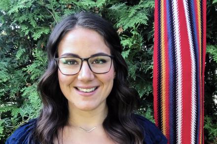 Cassidy Caron smiling with a Metis sash in background