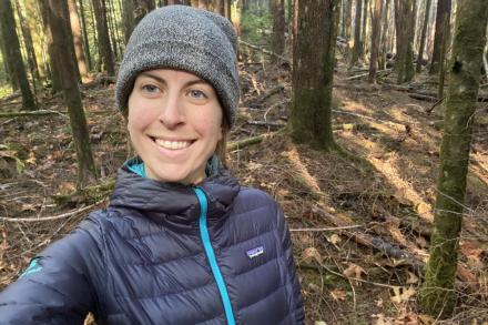 Nadia Linning standing in the woods and smiling at the camera