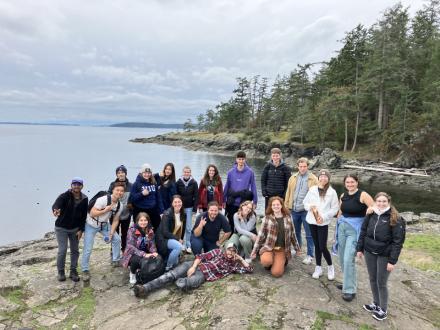 Group photo with a view of the ocean and trees behind them