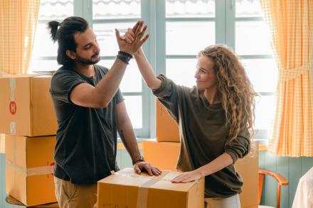 Students high fiving over moving boxes