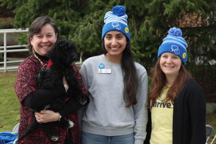 Three people pose, one of whom is holding a dog